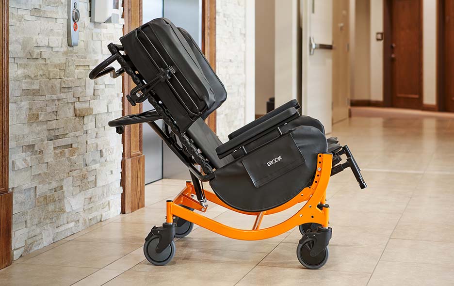 A Broda Wheelchair tilted   in a facility hallway