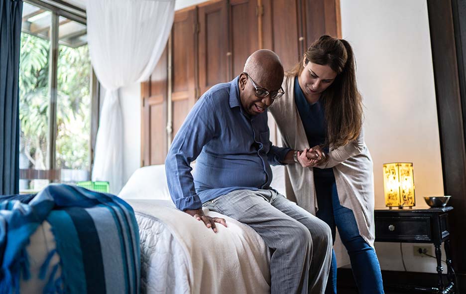 Patient getting out of bed with the support of a caregiver