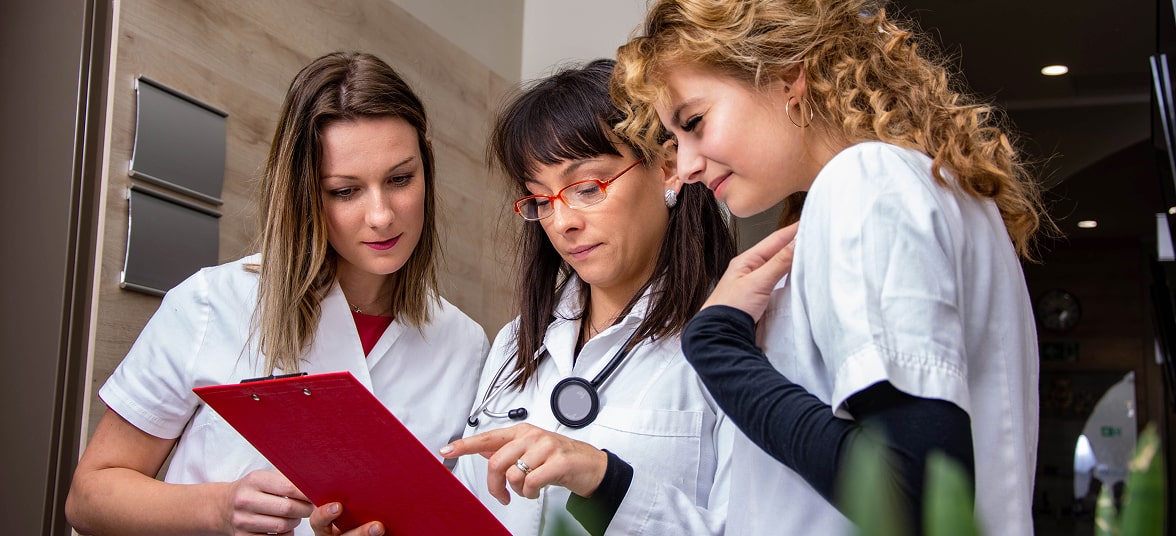 Three clinicians holding a clipboard