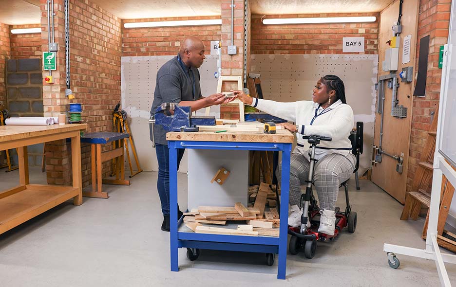 Young woman with a motorized wheelchair collaborating in a wood shop