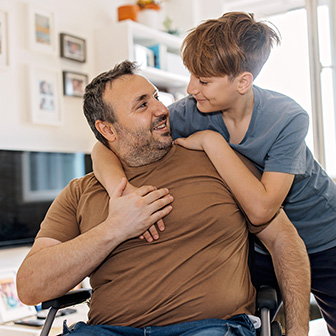Father in a wheelchair being hugged by his son