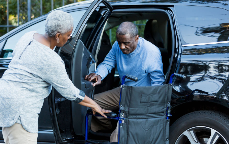 Women Assisting a Man with Exiting Vehicle into a Wheelchair
