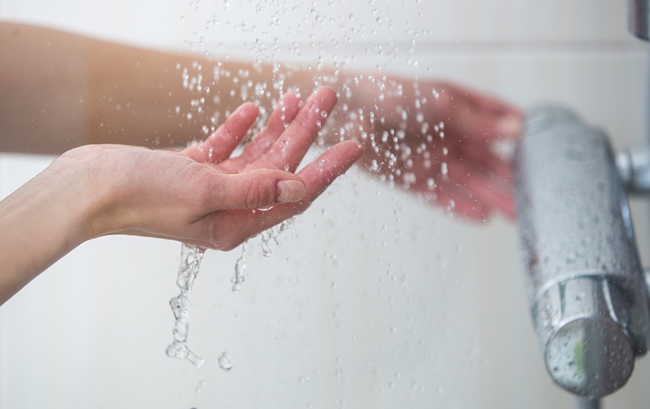 close up of hands feeling the falling water in the shower