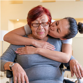 Young girl hugging her smiling grandmother from behind