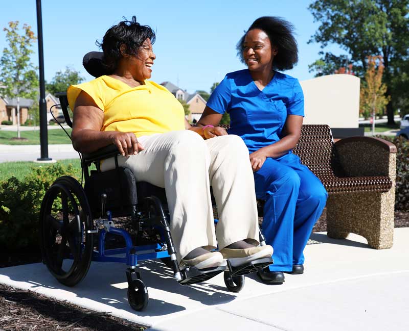 Caregiver Accompanying Lady in a Rehab Wheelchair