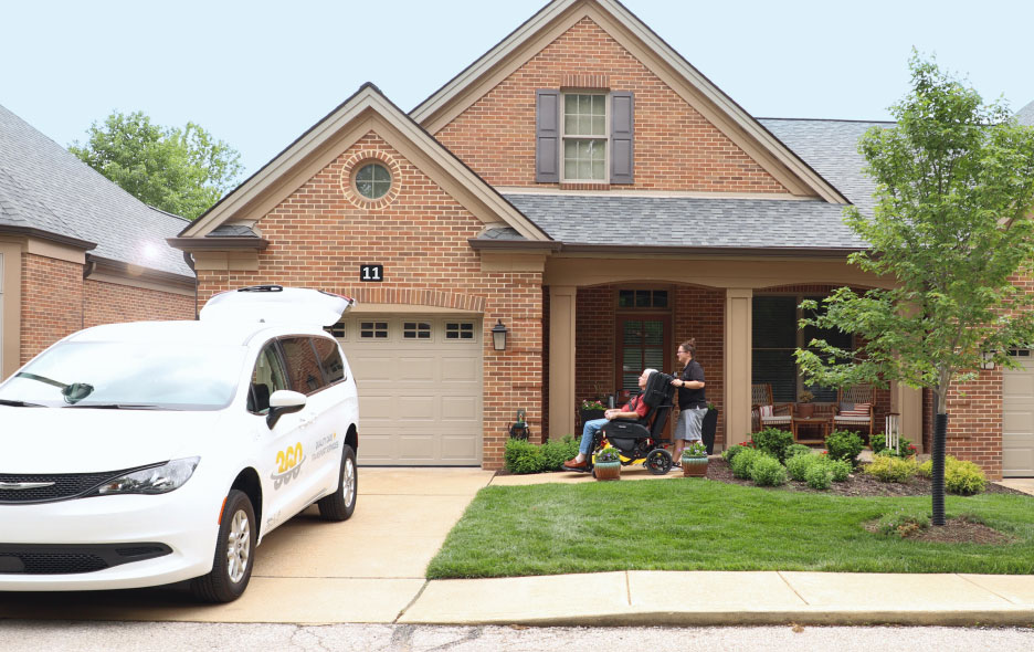 Far Away Shot of a Man In a Traversa Chair Being Pushed From Behind by a Healthcare Worker