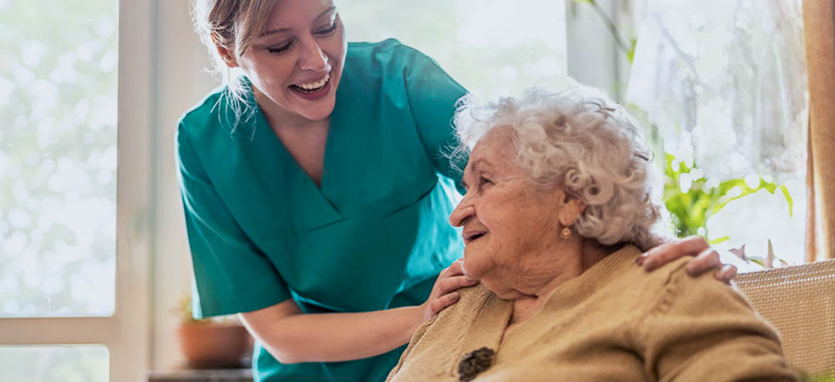 A caregiver leaning over to assist a senior woman