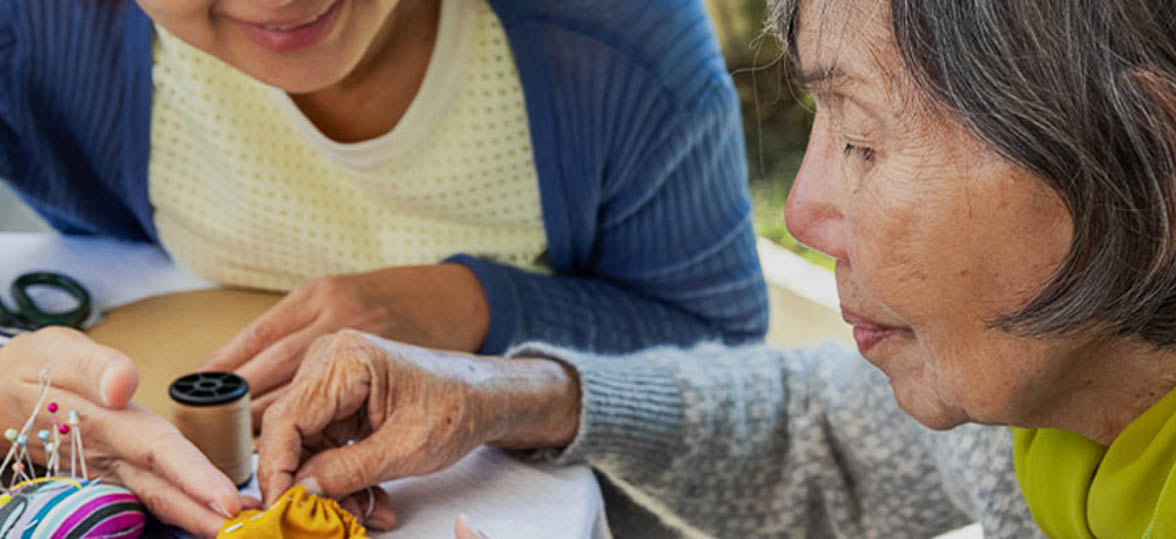 Elderly woman crafting with a caregiver