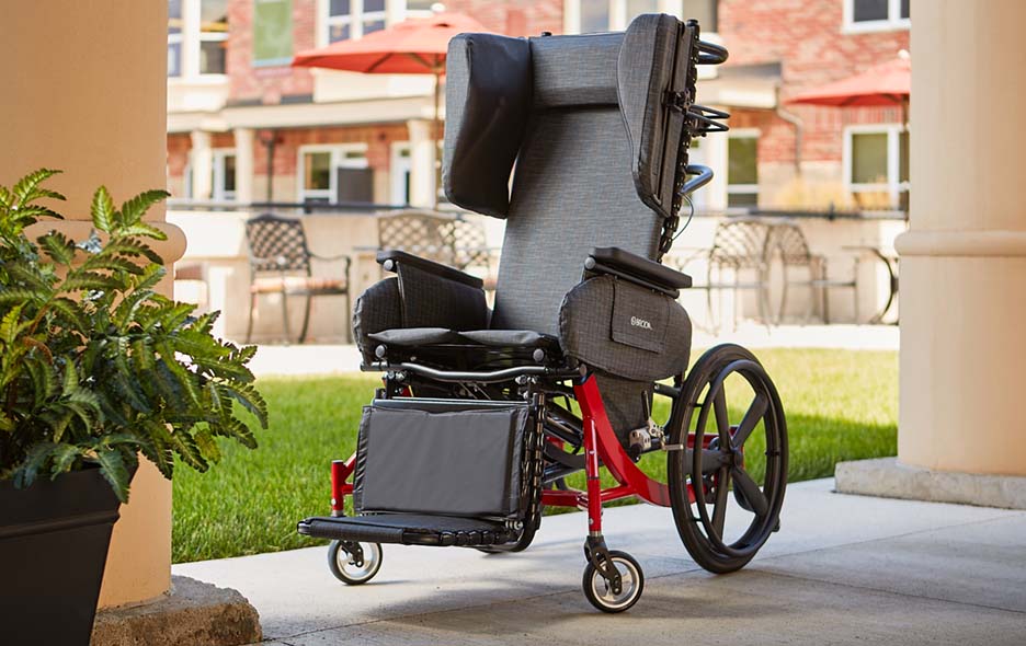 A positioning wheelchair on the outdoor patio of a long term care facility