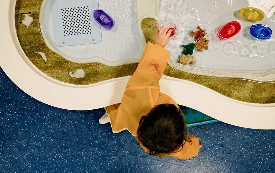 An overhead view of a child playing at a sensory water table