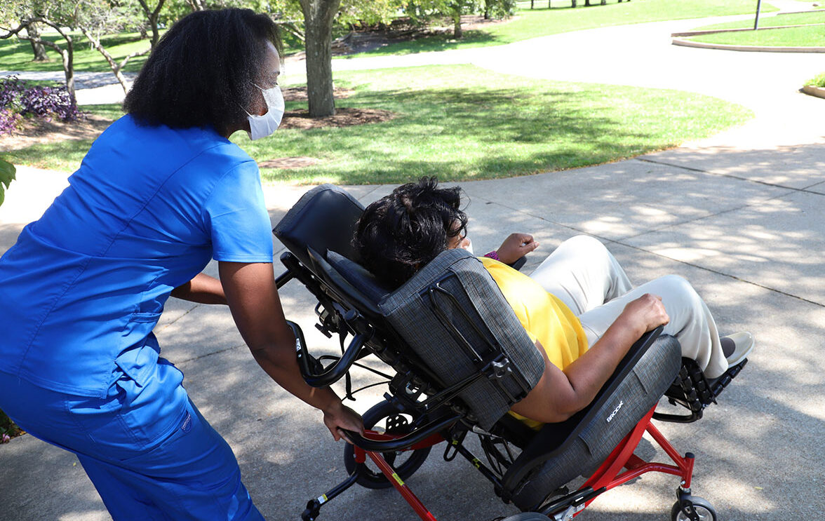 Nurse tilts a wheelchair for the woman seated in the wheelchair